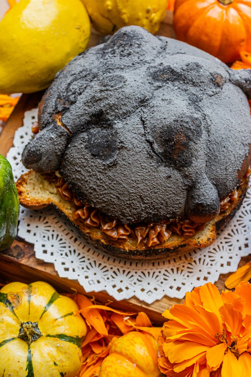 festive black pan de muerto surrounded by gourds